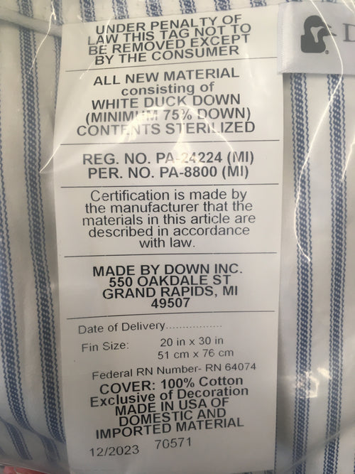 Close-up of a pillow tag detailing white duck down filling with minimum 75% down, sterilized contents, 100% cotton cover, made in USA, fitting Home & Decor, Home Textiles, Best Sellers, and Promo Eligible collections.