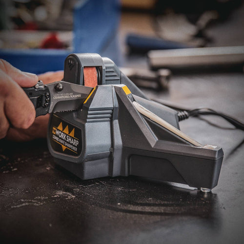 Person sharpening a serrated knife on a compact Work Sharp Combo Knife Sharpener with powered abrasive belt and manual ceramic honing rod, ideal for sharpening in Farm, Garden & Tool and Kitchen & Food collections.