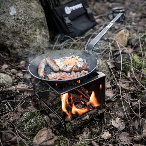 Compact steel camping stove with a sturdy firepan holding a frying pan cooking egg, sausage, and bacon outdoors, ideal for Farm, Garden & Tool, Camping, Emergency Supplies, and Best Sellers collections.