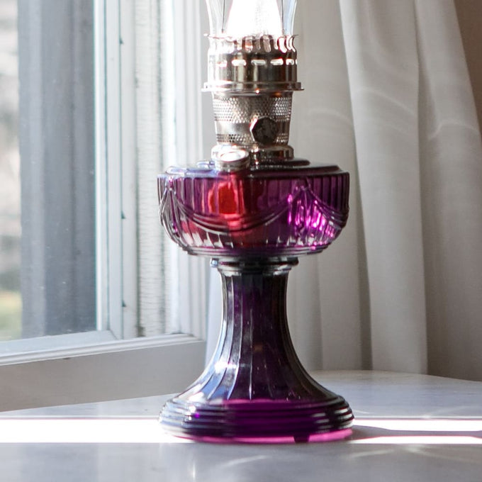 Handcrafted glass oil lamp with a rich purple Lincoln Drape base, clear tall chimney, and polished brass burner, ideal for Farm, Garden & Tool, Lamps & Lighting, Oil Lamps, Table Lamps, Best Sellers, Homesteading, and Promo Eligible collections.