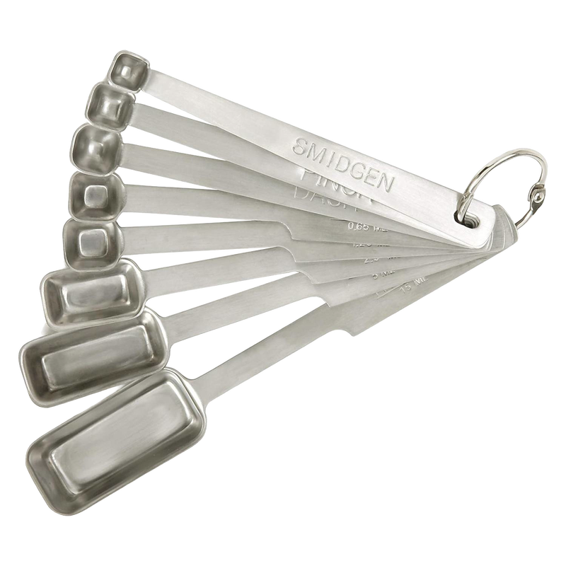 Set of eight stainless steel measuring spoons with elongated deep bowls, including smidgen, pinch, and dash sizes, designed for precise kitchen use in baking and food prep collections.