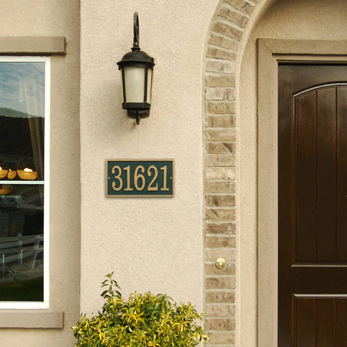 Green and gold rectangular address plaque with raised numbers mounted beside a dark wood door and beige stucco wall, handcrafted in USA, featured in Home & Decor, Mailboxes and Address Signs, Best Sellers, and Promo Eligible collections.