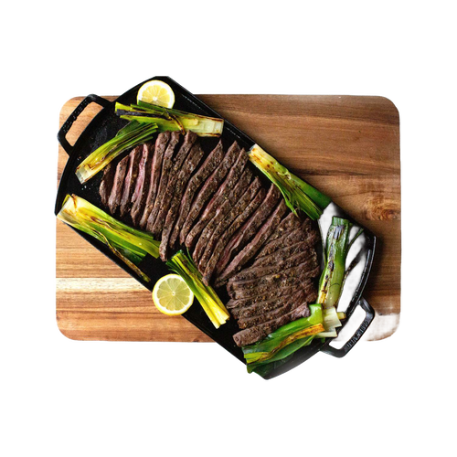 Handcrafted lightweight cast iron double burner griddle with perfectly sliced flank steak, grilled scallions, and lemon wedges on a wooden cutting board, ideal for Kitchen & Food and Cast Iron collections.