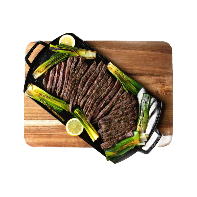 Handcrafted lightweight cast iron double burner griddle with perfectly sliced flank steak, grilled scallions, and lemon wedges on a wooden cutting board, ideal for Kitchen & Food and Cast Iron collections.