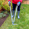 Person using long-handled lawn shears with sharp blades and tubular steel handles to trim grass edges along a flowerbed, suitable for farm, garden, and lawncare tasks.