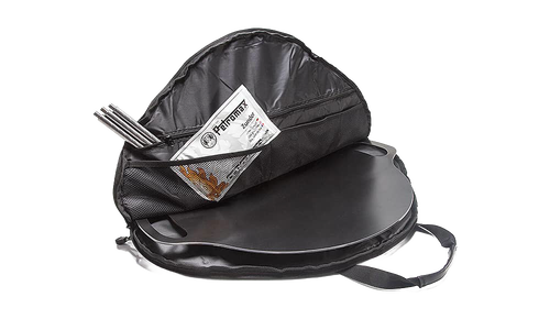 Black durable circular transport bag opened to reveal a flat griddle inside, featuring interior mesh pockets holding metal tools and a manual, suitable for camping and farm use.