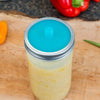 Glass jar sealed with a vibrant blue silicone fermentation lid and metal band, designed for small batch fermenting in kitchen, food preservation, and homesteading collections.
