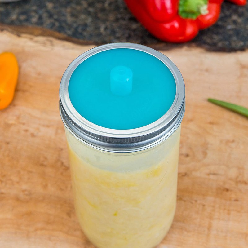 Glass jar sealed with a vibrant blue silicone fermentation lid and metal band, designed for small batch fermenting in kitchen, food preservation, and homesteading collections.