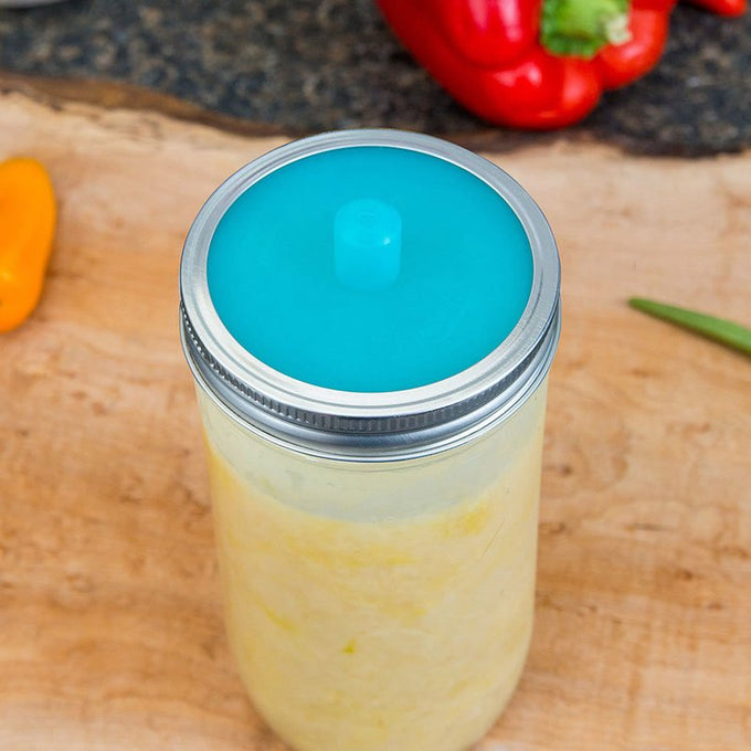 Glass jar sealed with a vibrant blue silicone fermentation lid and metal band, designed for small batch fermenting in kitchen, food preservation, and homesteading collections.