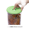 Hand pressing the valve on a green lid sealing a clear vacuum container filled with pretzels, designed for food preservation in Kitchen & Food and Storage collections.
