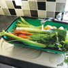 Green colander trug with built-in legs and carry handles washing freshly harvested carrots, celery, potatoes, and green beans under kitchen faucet, featured in Farm, Garden & Tool and Garden Accessories collections.