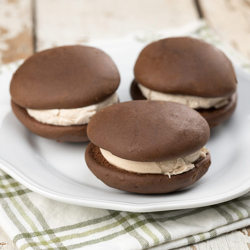 Three soft, cake-like chocolate cookies filled with creamy maple-flavored filling on a white plate, handcrafted in the USA, suitable for Kitchen & Food and Snacks and Sweets collections.