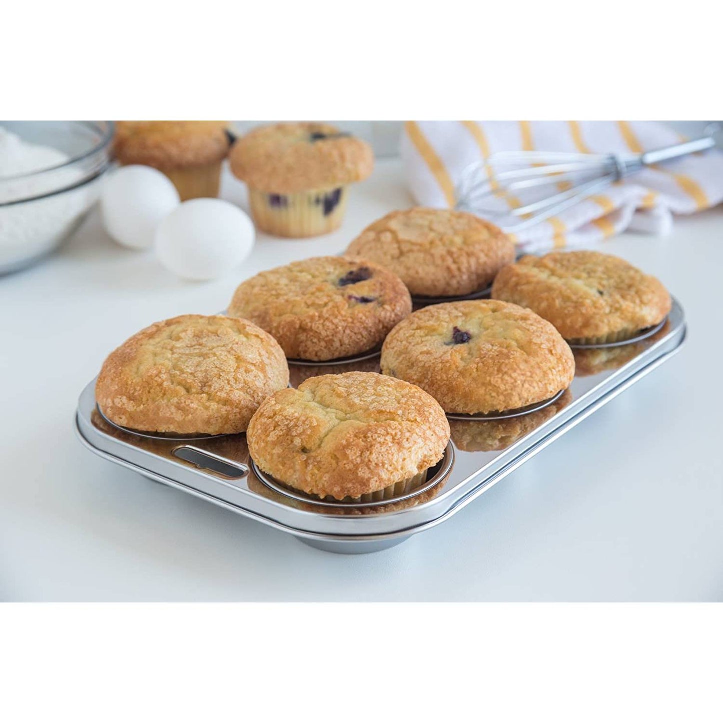Six golden muffins baked in a sleek stainless steel pan with a smooth, rust-resistant surface, surrounded by baking ingredients on a clean kitchen counter, featured in Kitchen & Food, Cookware, Baking Supplies, Pots and Pans, Best Sellers, and Promo Eligible collections.