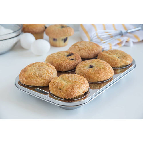 Six golden muffins baked in a sleek stainless steel pan with a smooth, rust-resistant surface, surrounded by baking ingredients on a clean kitchen counter, featured in Kitchen & Food, Cookware, Baking Supplies, Pots and Pans, Best Sellers, and Promo Eligible collections.