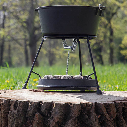 Outdoor cast iron Dutch oven with flat base, standing on a tripod over charcoal briquettes, ideal for open-air cooking, featured in Kitchen & Food, Cookware, Cast Iron, Best Sellers, and Promo Eligible collections.