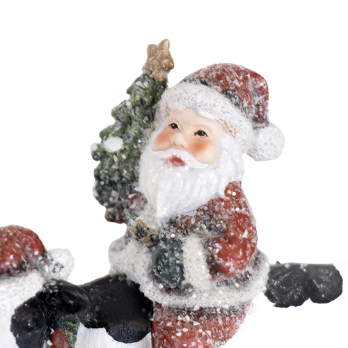 Charming handcrafted resin Santa figurine holding a Christmas tree, surrounded by snow accents, adding festive cheer to Home & Decor, Holiday Decor, Best Sellers, and Promo Eligible collections.