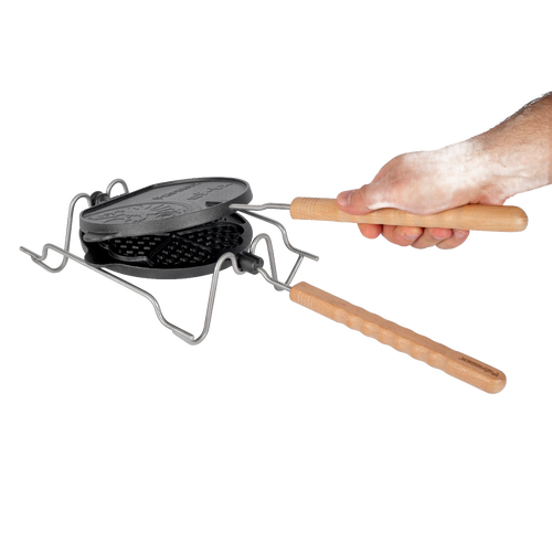 Handcrafted cast iron rotating waffle iron with wooden handles resting on a folding metal stand, designed for outdoor camping, farm, garden, and tool enthusiasts.