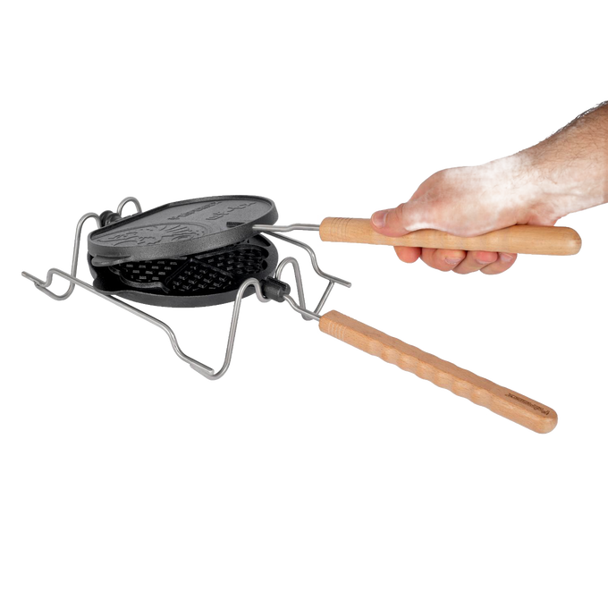 Handcrafted cast iron rotating waffle iron with wooden handles resting on a folding metal stand, designed for outdoor camping, farm, garden, and tool enthusiasts.