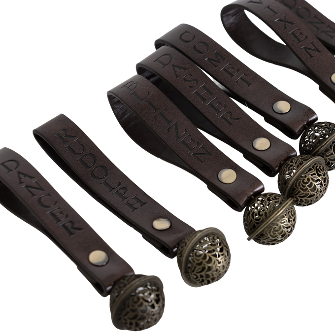 Set of nine handcrafted ornament bells with engraved brown leather straps featuring names of Santa’s reindeer, adorned with intricate metal bell accents for Home & Decor, Holiday Decor, and Best Sellers collections.