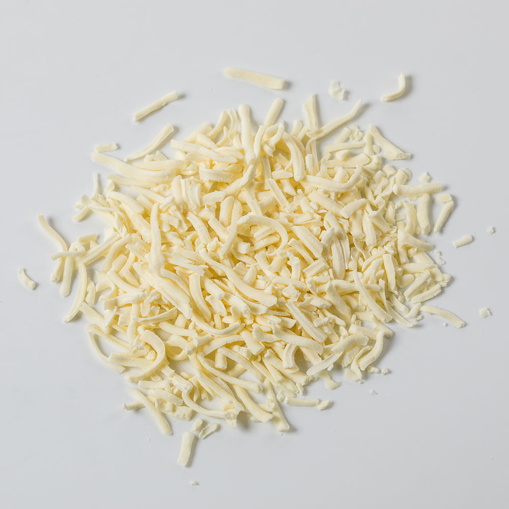 Pile of pale yellow shredded Monterey Jack cheese in freeze-dried form, shown on a plain white background, suitable for emergency food supplies and pantry use.
