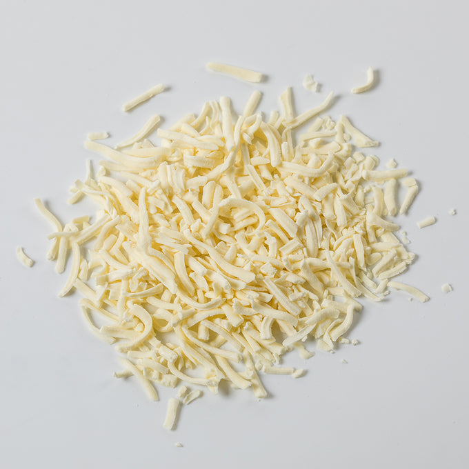 Pile of pale yellow shredded Monterey Jack cheese in freeze-dried form, shown on a plain white background, suitable for emergency food supplies and pantry use.