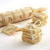 Handcrafted wooden rolling pin with carved springerle patterns next to stacks of square embossed cookies tied with ribbon, featured in Kitchen & Food, Baking Supplies, and Best Sellers collections.