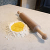 Handcrafted unfinished cherry wood noodle cutter resting on a kitchen counter next to a well of flour with cracked eggs, showcasing a practical tool for Kitchen & Food, Food Prep.