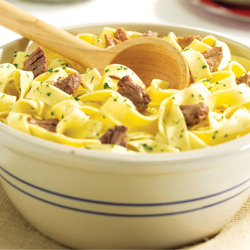 Creamy bowl of wide egg noodles mixed with tender chunks of handcrafted canned beef, garnished with fresh herbs and stirred with a wooden spoon, ideal for Farm, Garden & Tool and Emergency Supplies collections.