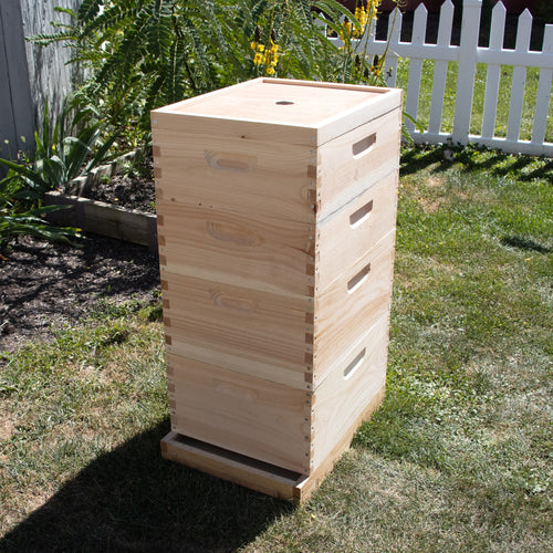 Handcrafted Amish-made wooden bee hive with multiple stacked frames, designed for chemical-free beekeeping, showcased outdoors in a sunny garden setting.