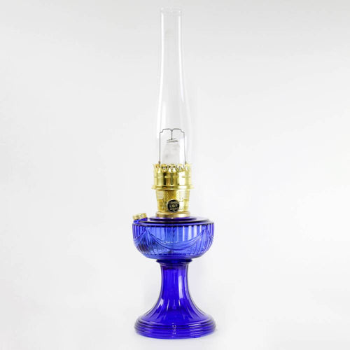 Handcrafted cobalt glass oil lamp with brass burner and tall clear chimney, featuring a vintage design, ideal for Lamps & Lighting, Oil Lamps, Table Lamps, Best Sellers, and Promo Eligible collections.
