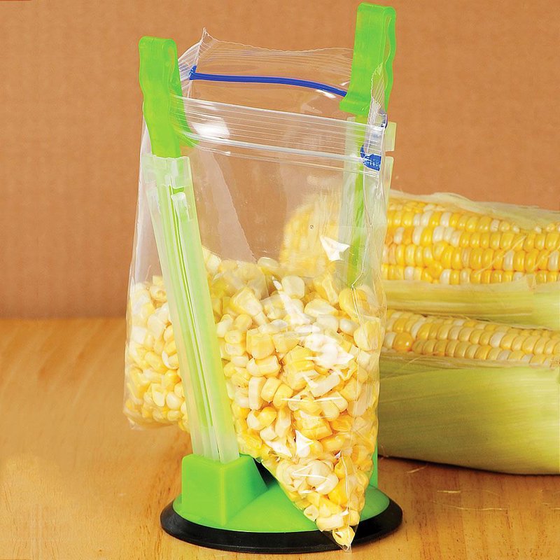 Green plastic bag holder with suction base keeping a zipper storage bag open for filling with corn kernels, designed for hands-free food preparation in Kitchen & Food, Kitchen Gadgets, and Cooking and Baking Helpers collections.