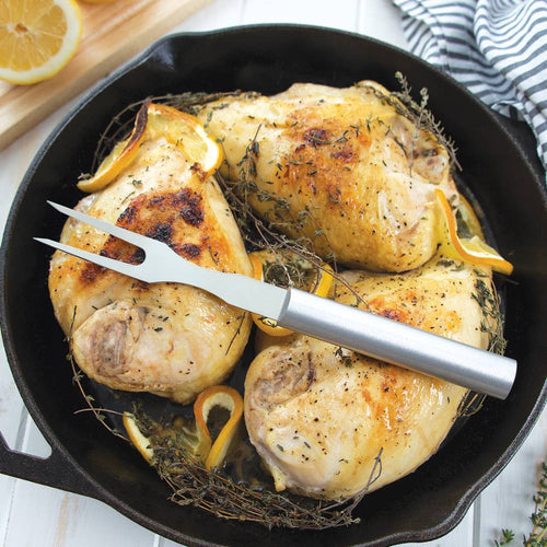 High-quality stainless steel carving fork resting on golden roasted chicken thighs garnished with lemon slices and fresh herbs in a cast iron skillet, ideal for Kitchen & Food, Storage and Serving, USA Made, Best Sellers, and Promo Eligible collections.