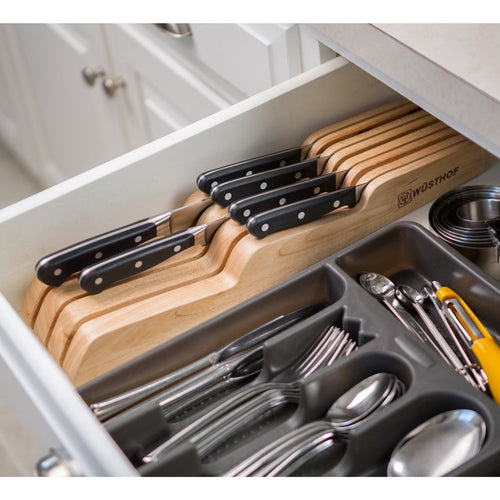 Wooden drawer organizer holding seven Wusthof knives with black handles neatly arranged next to a utensil tray, featured in kitchen accessories and food prep collections.