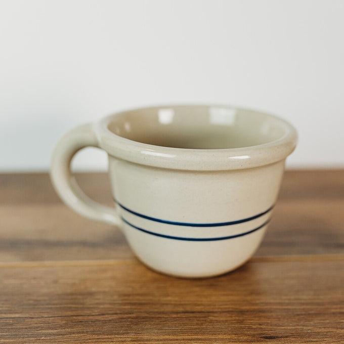 Handcrafted stoneware bowl with a handle, featuring natural color and two blue stripes, perfect for Kitchen & Food, Dinnerware, USA Made, Best Sellers, and Promo Eligible collections.