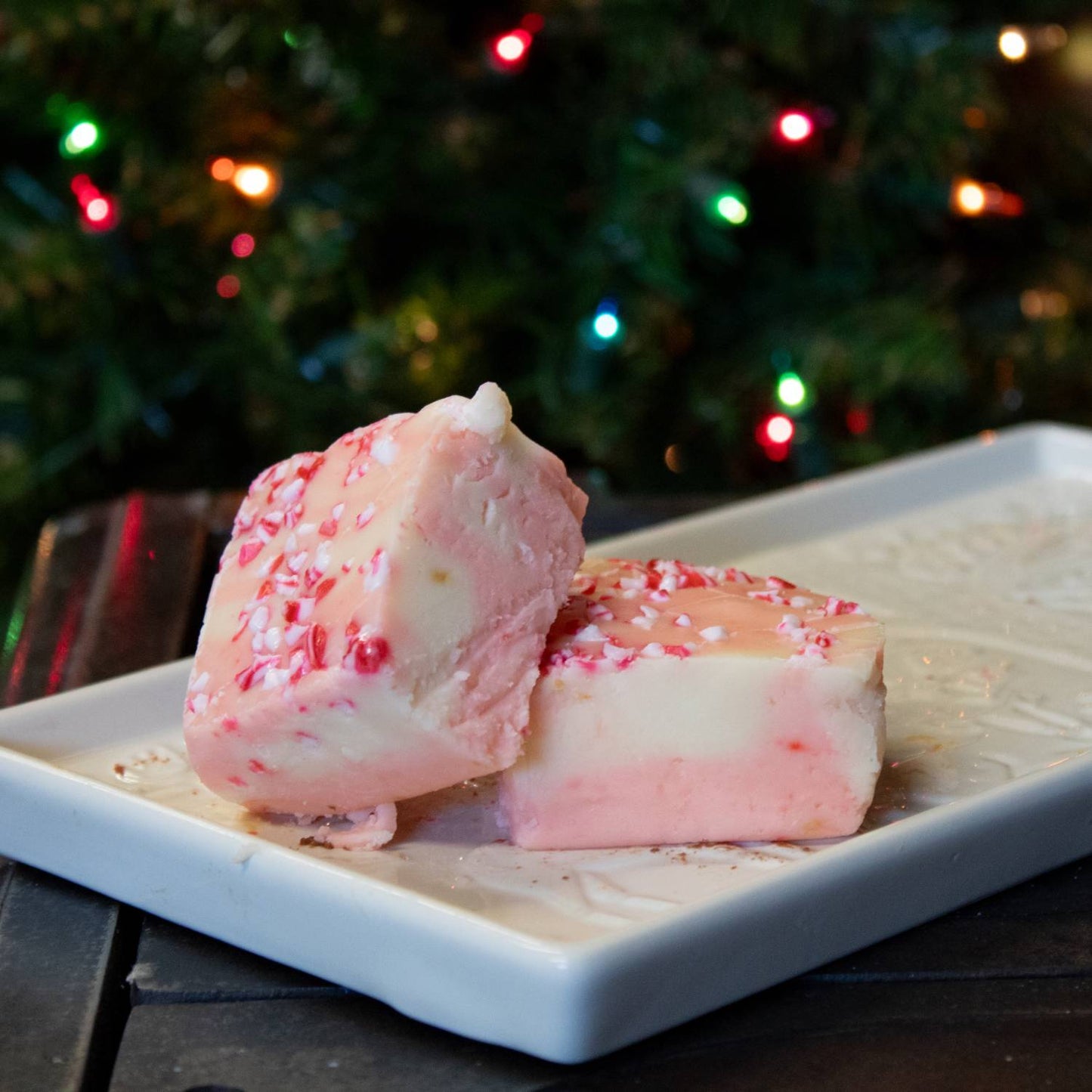 Two handcrafted peppermint fudge pieces with creamy layered pink and white colors topped with crushed candy, displayed on a white plate for Kitchen & Food, Snacks and Sweets, USA Made collections.