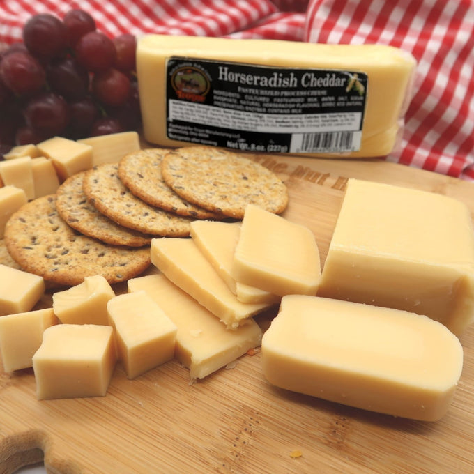 Handcrafted shelf-stable horseradish cheddar cheese cut into cubes and slices on a wooden board with crackers and grapes, ideal for Kitchen & Food, Pantry, Snacks and Sweets, USA Made, and Best Sellers collections.
