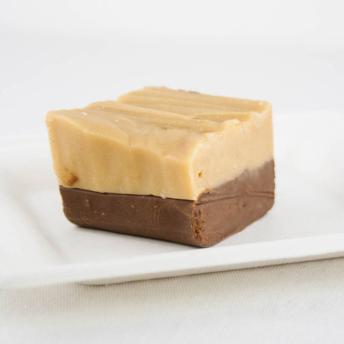Single handcrafted two-layer fudge piece with creamy caramel top and rich chocolate bottom on a white plate, featured in Kitchen & Food, Food, Snacks and Sweets, USA Made, Best Sellers, and Promo Eligible collections.