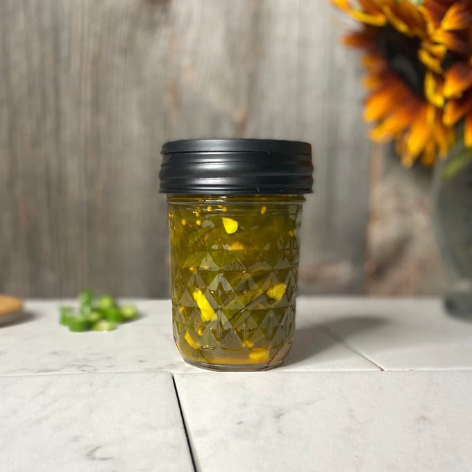 Handcrafted black flip top lid on a clear glass jar filled with preserved peppers, displayed on a white surface with rustic wood background and sunflower, suitable for Home & Decor and Kitchen Accessories collections.