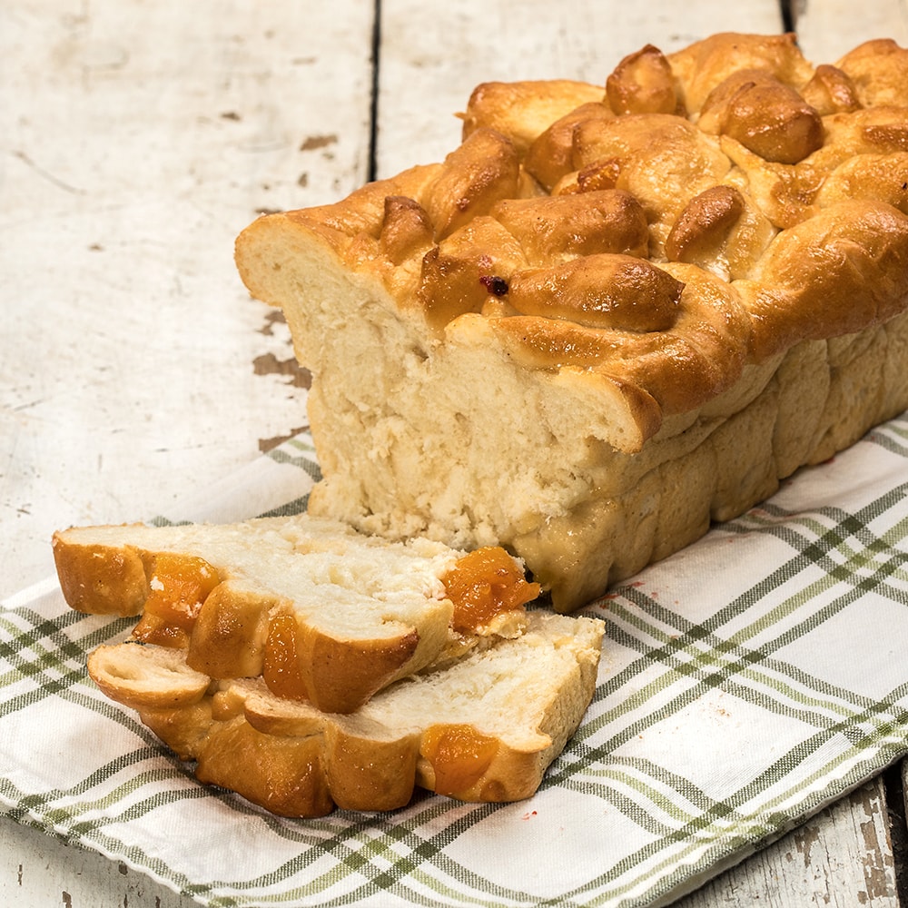 Sliced loaf of soft, freshly baked peach bread made with sweet peaches, displayed on a rustic cloth, ideal for Kitchen & Food, Snacks and Sweets, USA Made, and Best Sellers collections.