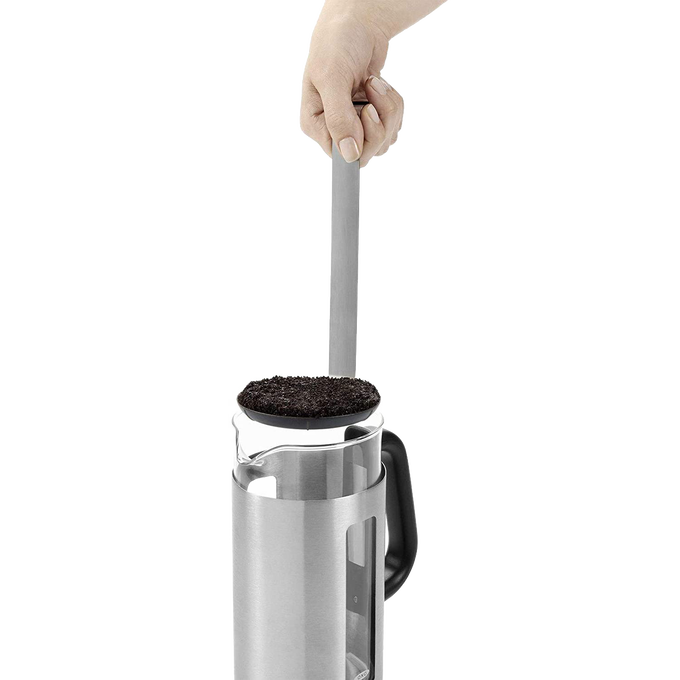 Hand using the GroundsLifter tool to lift used coffee grounds from a stainless steel and glass French press coffee maker with black handle, featured in Kitchen & Food and Brewing Coffee and Tea collections.