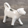 White porcelain cow-shaped creamer with a tail handle and spout mouth, handcrafted and microwave, oven, and dishwasher safe, ideal for Kitchen & Food and Dinnerware collections.
