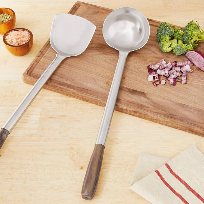 Set of two stainless steel wok utensils with wooden handles, featuring a spatula and ladle, displayed on a wooden cutting board with chopped vegetables, ideal for Kitchen & Food and Kitchen Gadgets collections.