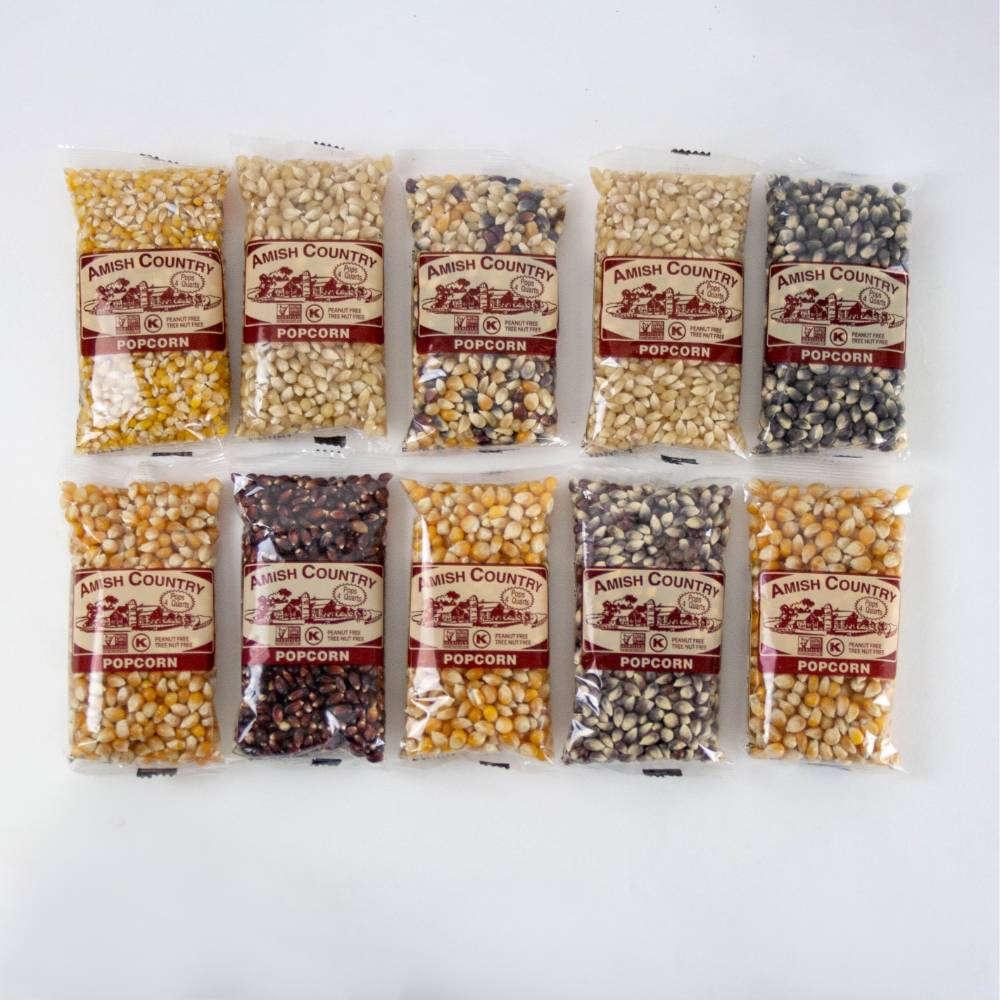 Ten small clear bags of Amish made popcorn kernels in a variety of colors and types, arranged in two rows on a white background, ideal for Kitchen & Food and USA Made collections.