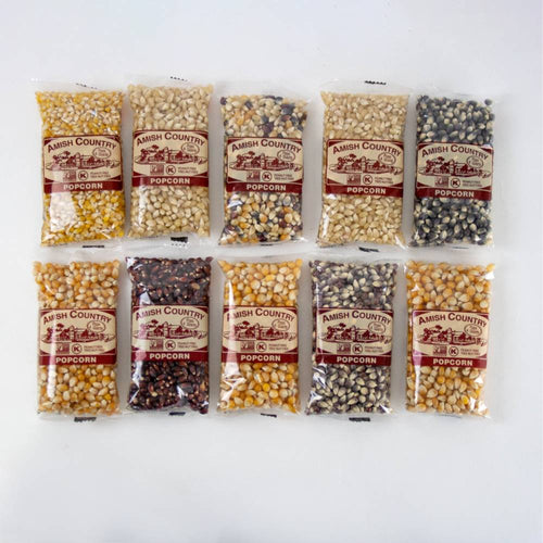 Ten small clear bags of Amish made popcorn kernels in a variety of colors and types, arranged in two rows on a white background, ideal for Kitchen & Food and USA Made collections.