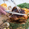 Handcrafted carving and boning knives with solid satin-finished recycled aluminum handles slicing a roasted chicken on a wooden board with fresh herbs, garlic, and citrus, featured in Farm, Garden & Tool, Kitchen & Food, Knives & Axes, Kitchen Knives, Food Prep, USA Made, and Best Sellers collections.