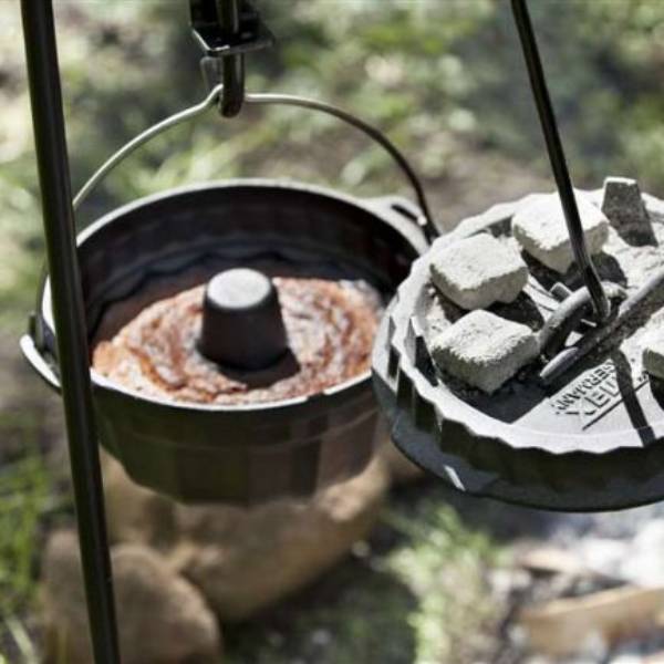Cast iron Dutch oven with baked bread inside and charcoal briquettes on a suspended cooking grate over an outdoor fire, ideal for Farm, Garden & Tool, Stoves, Camping, and Grilling collections.