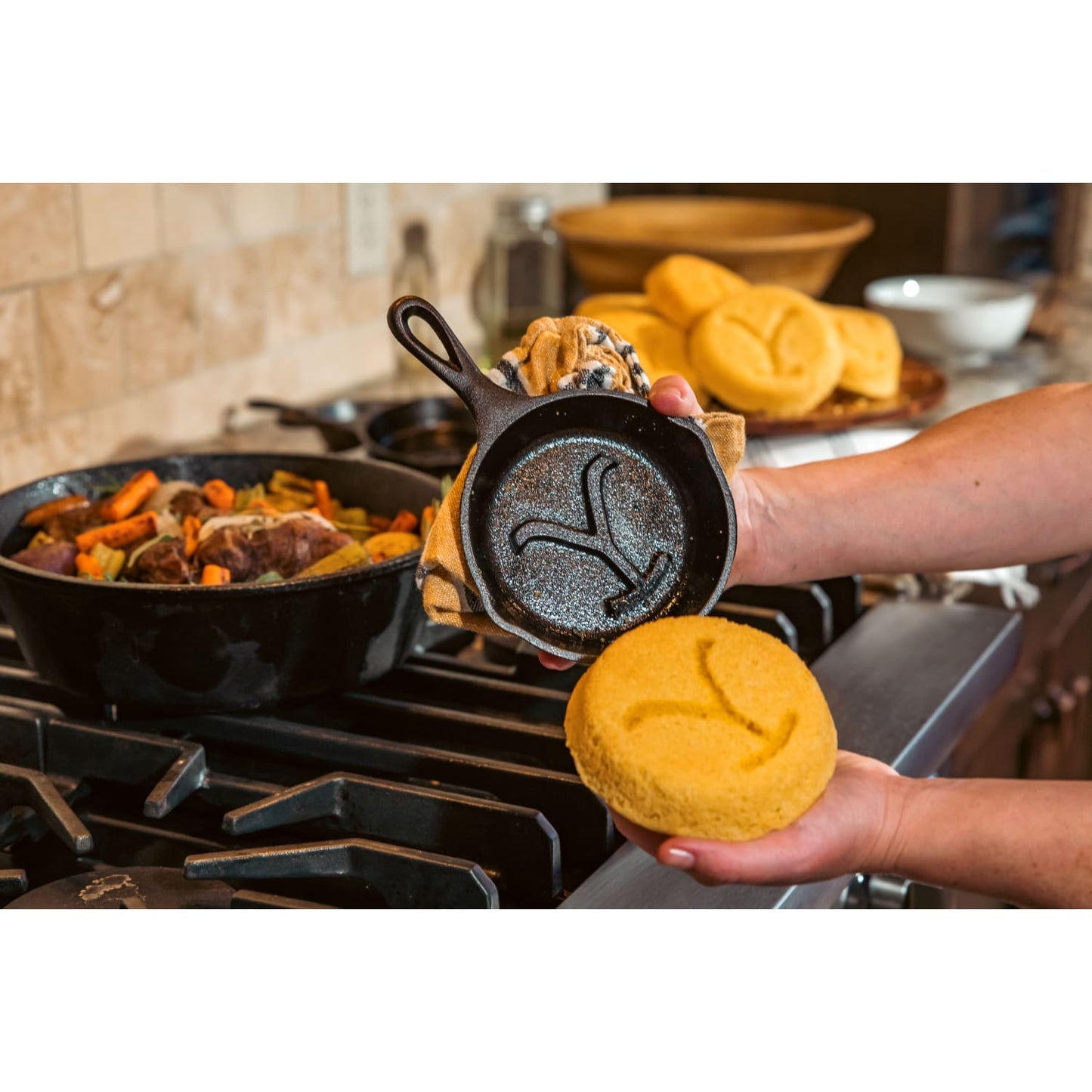 Handcrafted cast iron skillet in black featuring a raised power Y design, held alongside freshly baked cornbread embossed with the same emblem, perfect for Kitchen & Food and Cookware collections.