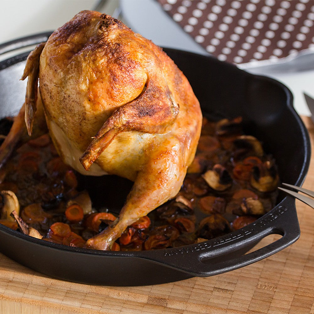 Golden roasted whole chicken standing upright in a cast iron poultry roaster filled with sautéed mushrooms and carrots, featured in Kitchen & Food, Cookware, and Cast Iron collections.