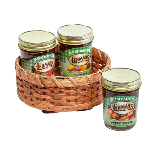 Handcrafted Amish-made rotating lazy Susan basket woven from basket reed with a poplar base, holding glass jars of homemade jams and preserves, ideal for kitchen accessories.