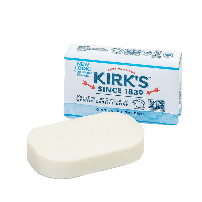 Bar of creamy white castile soap embossed with Kirk's branding, positioned in front of redesigned American-made packaging highlighting 100% premium coconut oil and gentle, natural formula, ideal for Health & Wellness, Grooming and Personal Hygiene, Soaps, USA Made, Best Sellers, and Promo Eligible collections.